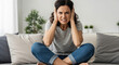 © StudioAi - A frustrated woman sits on a couch, covering her ears and expressing distress, capturing a moment of overwhelming emotion in a cozy home setting.