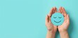 © guobao - Customer satisfaction concept with hands holding blue smiling face symbol on teal background for positive feedback