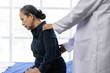 © Wasan - Female doctor diagnose a mature woman experiencing backache while resting in a hospital bed, delivering compassionate medical care.