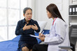 © Wasan - Senior woman describing chest pain symptoms to doctor in hospital room.