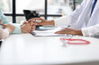 © Wasan - Doctor comforting patients by holding their hands and explaining medical document.