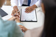 © Wasan - Doctor holding hands with patients, demonstrating empathy while explaining a medical document with a pen in medical exam.