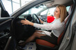 © Jelena - Happy woman test driving new car at dealership