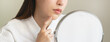 © Pormezz - Asian young woman looking face skin in the mirror have a red rash on her face from cosmetic allergy