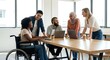 © Yuliia - Diverse business team collaborating around laptop in modern office with natural light. Includes woman in wheelchair promoting workplace inclusion and accessibility.