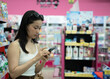 © Nazareno - Young woman shopping browsing products using smartphone in retail store