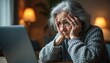 © Vadym - Elderly woman worries looking at laptop screen. She holds head in hands feeling stressed and confused. Concerned senior person has tech problems at home, showing mental anguish and deep sadness.