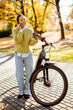 © BGStock72 - Woman enjoying an autumn day by the park with her bicycle and phone