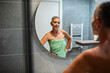 © Marko Geber - Confident mature woman in towel looking in bathroom mirror