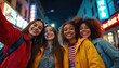 © Pete - Four happy young women take selfie at night city street with neon signs. Friends enjoy urban adventure on vacation, smiling together, sharing fun moments.