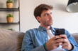 © Daniel - Dreamy pensive freelance man thinking over work project ideas on home office couch, using phone, looking at window away, serious at interesting thoughts, future business vision.