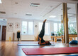 © Soloviova Liudmyla - Happy young woman in black sportswear practicing pilates leg stretch on blue mat in bright gym studio while doing flexibility workout for healthy lifestyle and professional fitness body training.