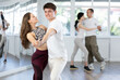© JackF - Couple of smiling young guy and girl enjoying slow foxtrot in dance studio. Amateur ballroom dancing concept..
