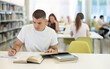 © JackF - European guy is sitting at a table, reading a book and making notes in a notebook, he is preparing to enter the university in the new academic year. Students study in the library