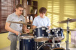 © New Africa - Teenage boy learning how to play drums with music teacher indoors