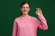 © New Africa - Happy woman showing okay gesture on green background