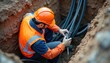 © Viktor - Construction worker in safety gear installs cables underground. Technician handles fiber optic wires in a trench. Professional man works on utility infrastructure project for internet connection.
