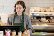 © JackF - Young female barista in apron at cash register in coffee shop