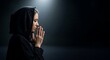 © Tulippp - Solemn woman in head covering praying earnestly with clasped hands in soft, ethereal light