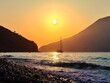 © Cristiano - Sunset over the sea with a sailing boat and distant islands, golden sky and reflective water