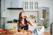 © laddawan - Healthy Asian woman holding fresh strawberries while preparing smoothie and salad at home kitchen. Clean eating, nutrition, fitness lifestyle