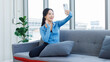 © Bangkok Click Studio - Asian young beautiful happy woman fit sporty active healthy in sportswear sitting cozy sofa taking selfie or video calling mobile smartphone after exercise training in living room wellness lifestyle.