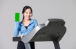 © Bangkok Click Studio - Asian young beautiful cheerful woman sport girl in sportswear exercise holding mobile smartphone with blank green screen showing on treadmill athlete training, gray background studio healthy wellness.