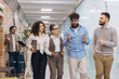 © anatoliycherkas - Diverse business professionals walking through office corridor, discussing work, team collaborating, and problem solving
