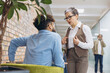 © anatoliycherkas - Mature female boss arguing with young male employee in office hallway, discussing corporate conflict