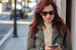 © tetxu - Woman in leather jacket using smartphone, focusing on digital communication and trendy urban fashion