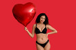 © Pixel-Shot - Beautiful young African-American woman in stylish black lingerie with air balloon in shape of heart on red background. Valentine's Day celebration