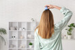 © Pixel-Shot - Young woman in pajamas using hair scalp massager at home, back view