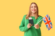 © Pixel-Shot - Beautiful young happy woman with UK flag, passport and ticket on yellow background