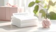 © Pure Imagination - Stack of White Towels with Pink Gift on Table in Bright Window Light