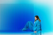 © Rendara Studio - Woman leaning beside blue translucent 3D panel in studio setting