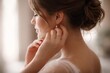 © Daria - Young woman adjusting earring near window in soft natural light, elegant lifestyle portrait with gentle mood, beauty routine, femininity and calm morning atmosphere