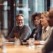 © Zain - Four people sit at a conference table in a glass office space talking and listening during a business meeting