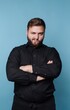 © bodnarphoto - Man stands with arms crossed and serious expression against blue background