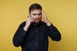 © bodnarphoto - Man speaks on phone with worried expression in front of yellow background during an uncertain moment in a modern setting
