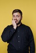 © bodnarphoto - Man shows nervous expression on yellow background during indoor photo session in casual setting