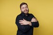 © bodnarphoto - Man smiles and embraces himself against a bright yellow background in a casual indoor setting