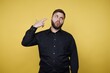 © bodnarphoto - Man poses with finger gun gesture against a yellow background during a casual moment