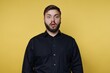 © bodnarphoto - Person shows surprise with wide eyes and mouth open in front of bright yellow background during indoor setting