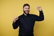 © bodnarphoto - Young man celebrates with raised fists against a bright yellow background during a lively moment at an event