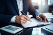 © nsit0108 - Businessman wearing a suit writing on a document while sitting at an office desk