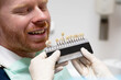© Ladanifer - Dentist with gloves holding a tooth shade guide near a smiling patient's mouth