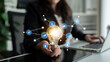 © InfiniteFlow - A businesswoman holds a glowing light bulb symbolizing ideas amidst digital icons representing various aspects of technology and innovation in a modern office. Tessel
