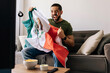 © kleberpicui - Happy Mexican soccer supporter celebrating at home while holding the national flag. Adult man enjoying the match on TV with snacks and drinks in a cozy living room.