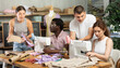 © JackF - Kind young male teacher helping students sew while other drawing on paper during sewing class