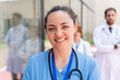 © StockMe - Caring medical professional smiling with diverse healthcare team standing outside hospital building